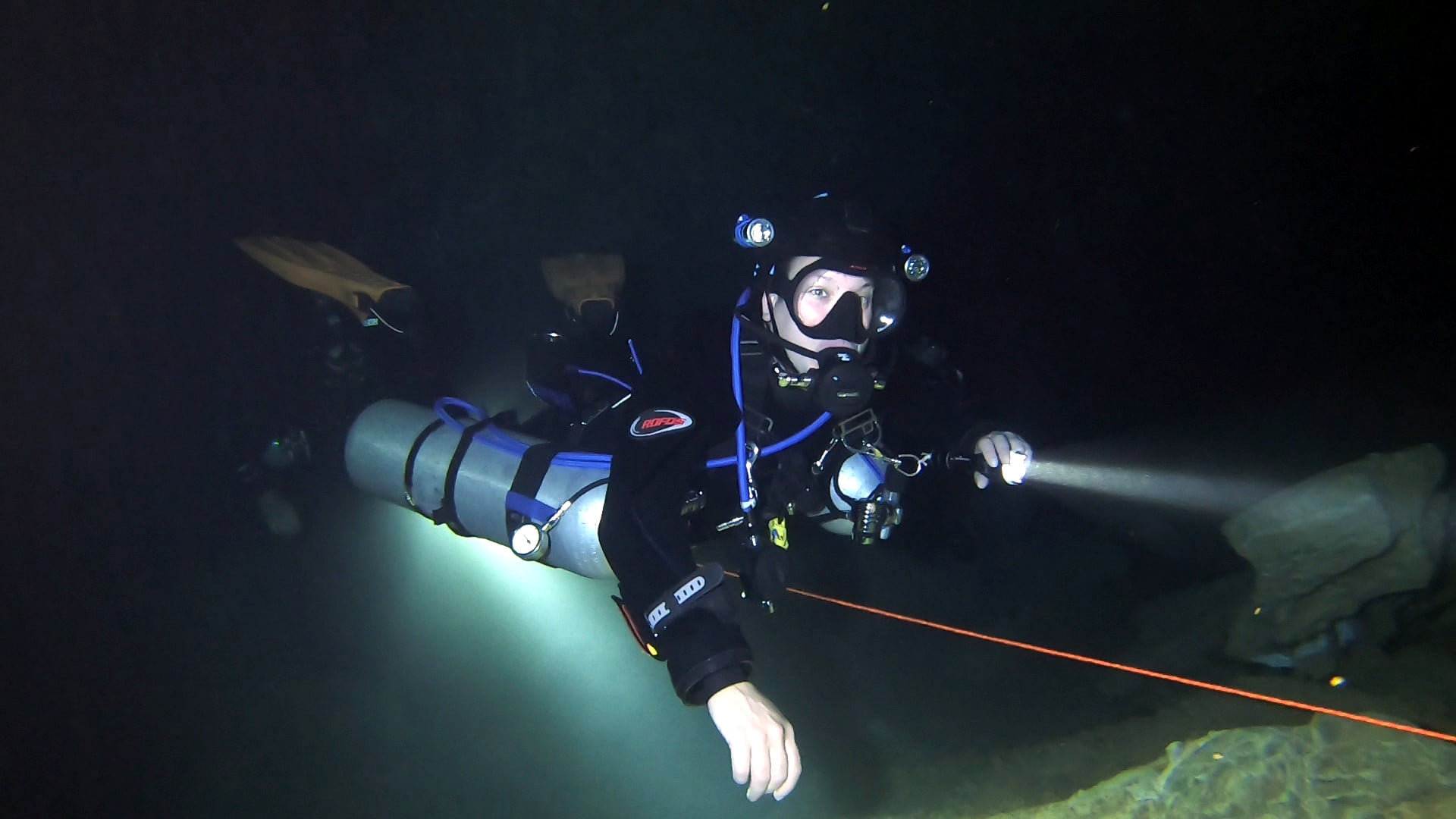 Sidemount diver in the cave with light beam