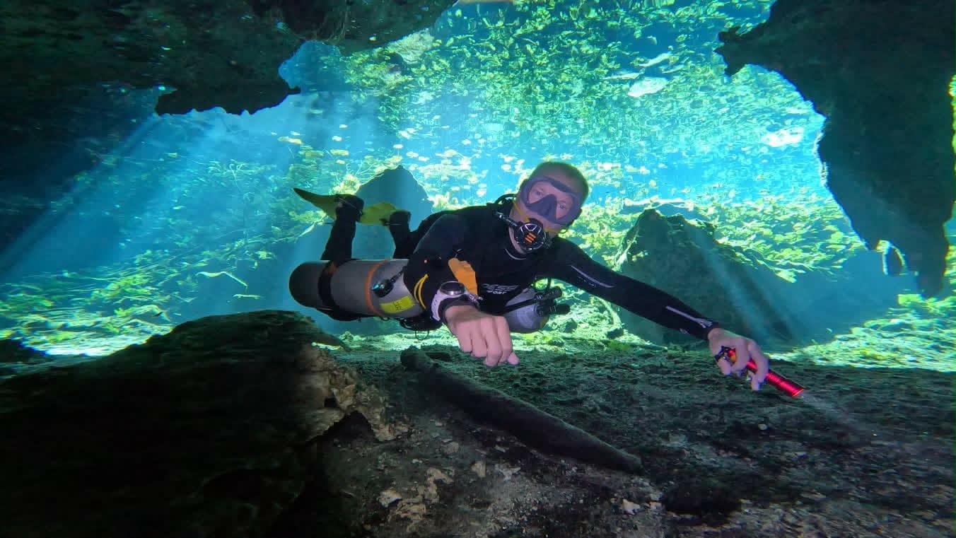 Diver in the light rays of Cueva del Agua cenote